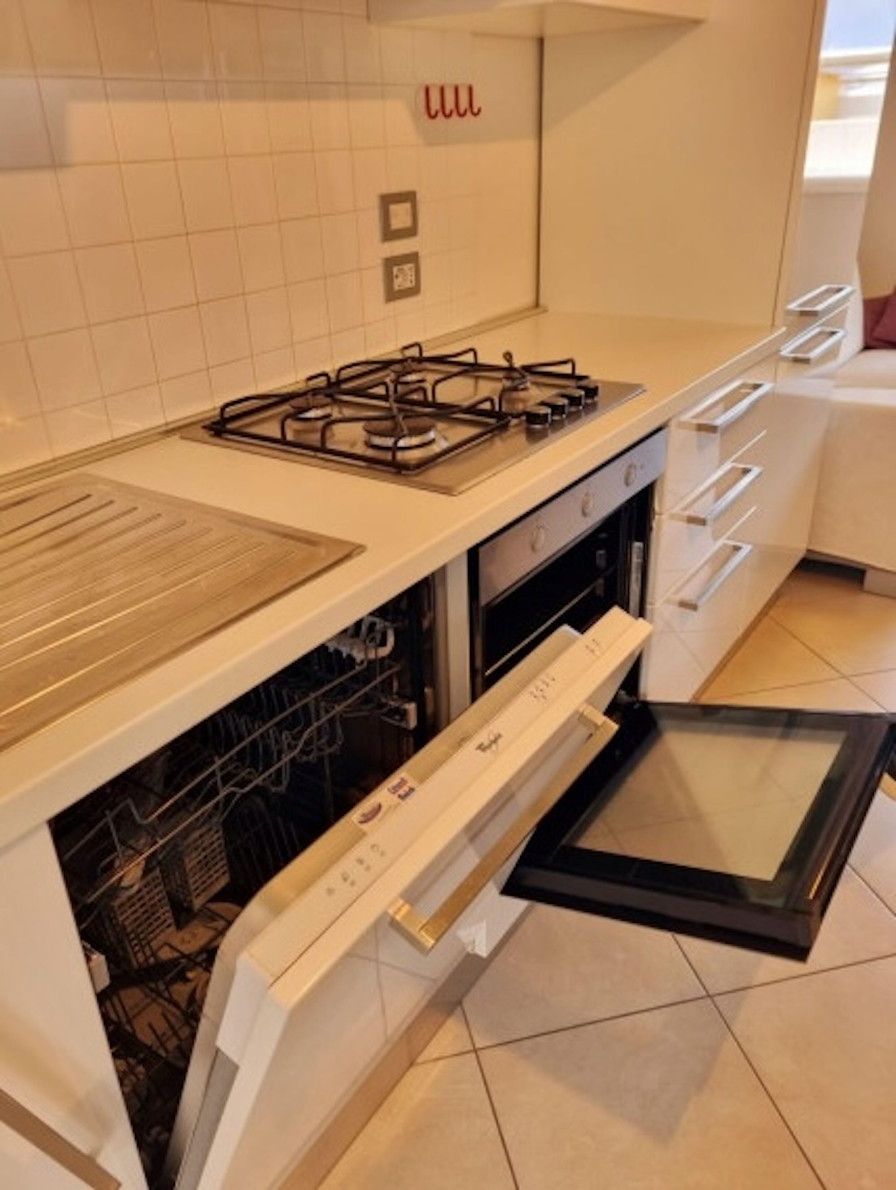 A modern kitchen with a gas stove, dishwasher, and a built-in oven.