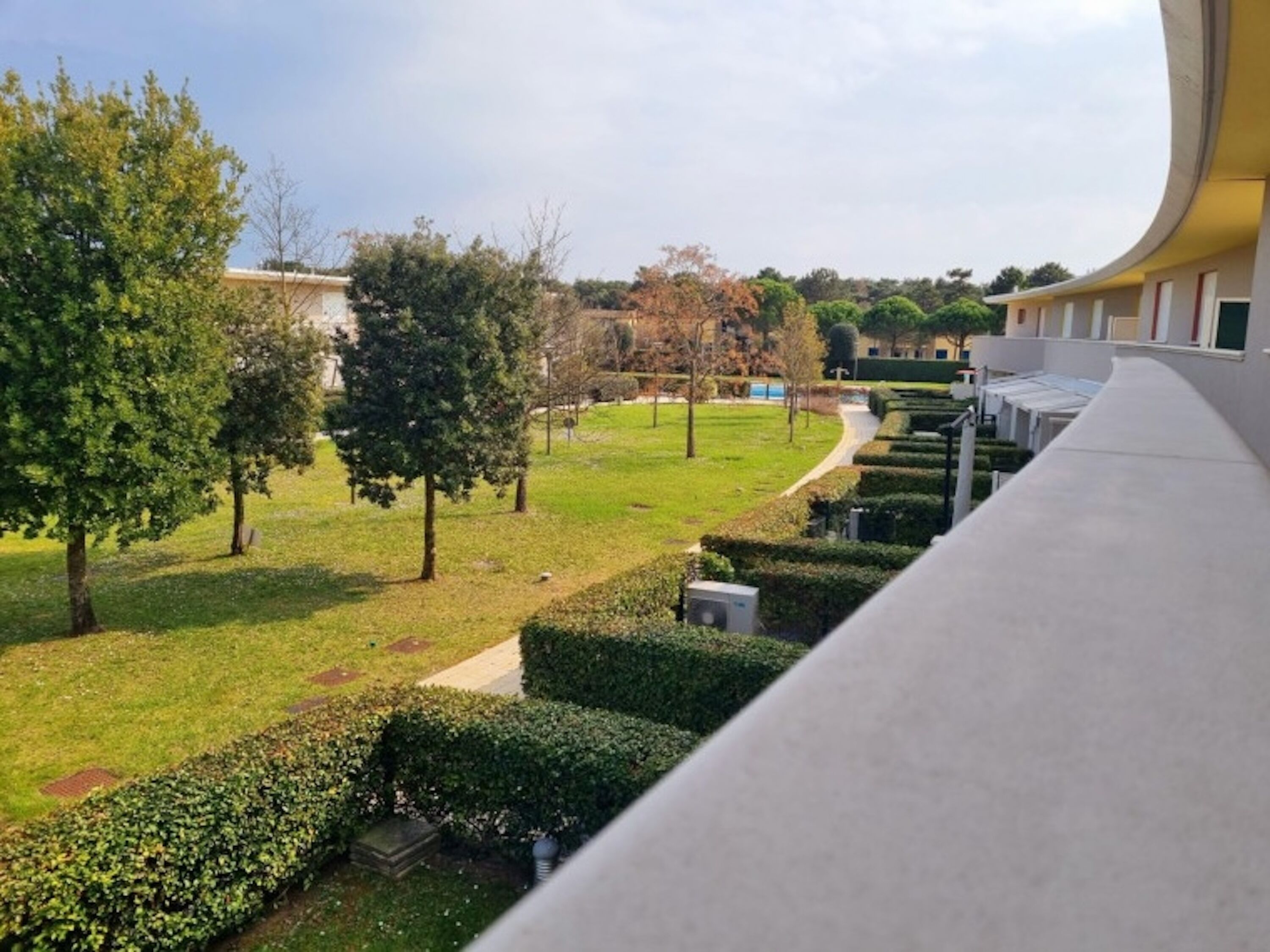 Une vue d’une cour avec des haies soigneusement taillées, un chemin et des arbres.