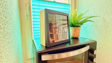 Ein schwarzes Toaster-Heizgerät mit Glastür, platziert auf einer Arbeitsplatte neben einem Fenster mit Jalousien.