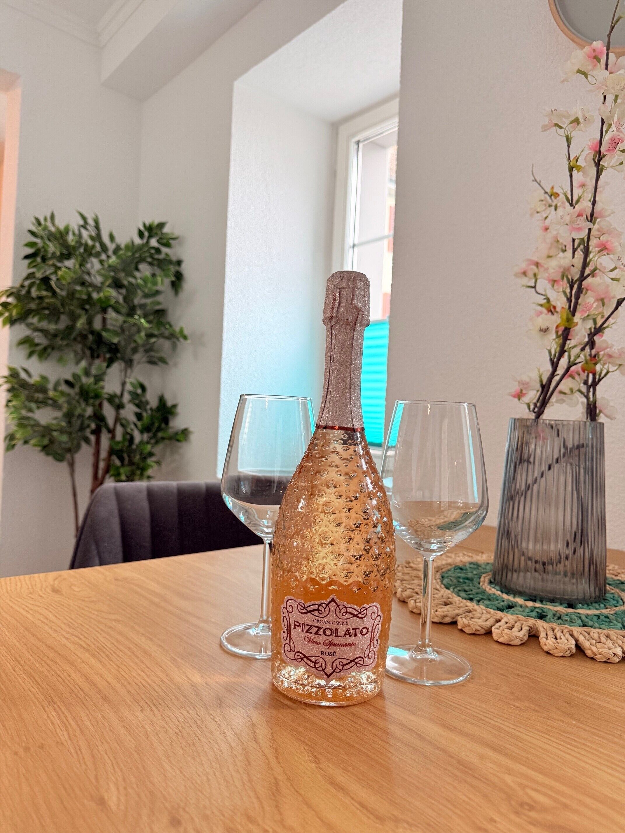 A bottle of organic wine on a wooden table with two empty glasses beside it.