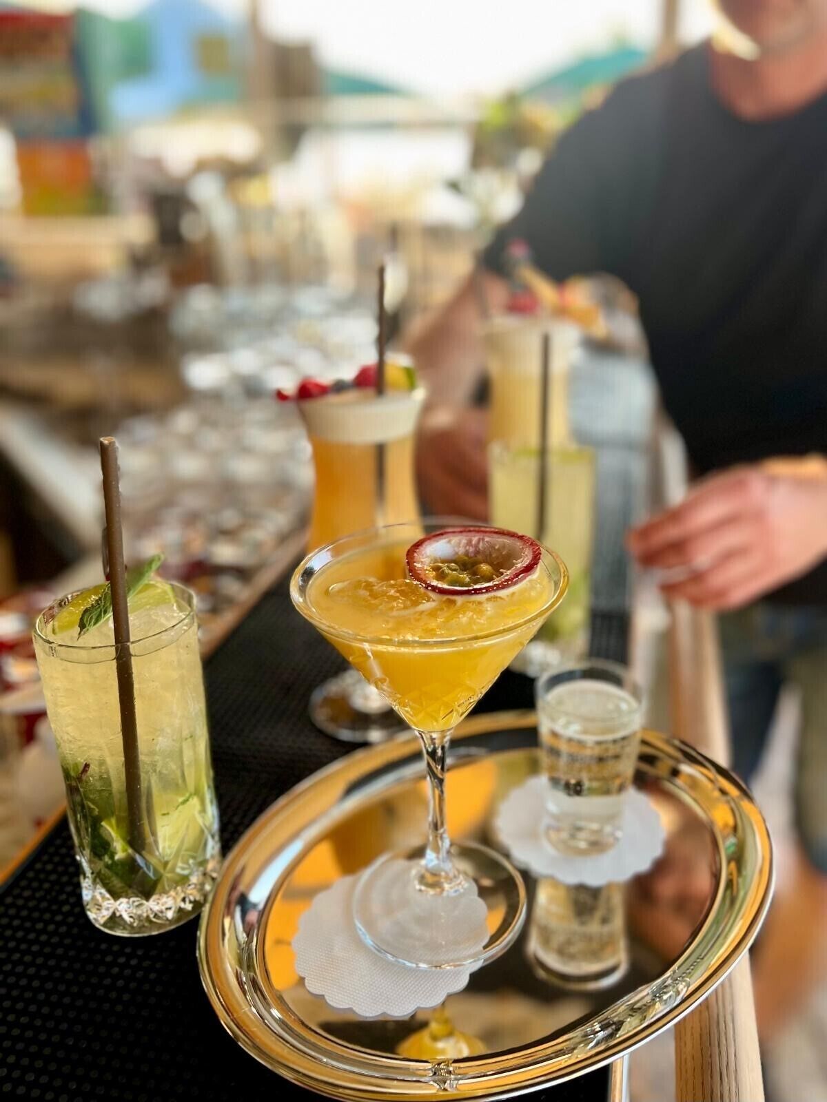 Un bar proposant une variété de boissons, notamment un martini garni de fruit de la passion, un grand verre avec une paille et un petit verre avec une paille.
