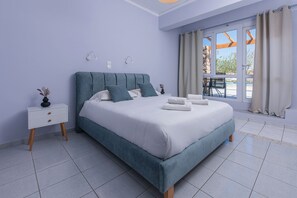 A bedroom with a bed, bedside tables, and a window with curtains. - GIN Wellness Hotel (Santorini)