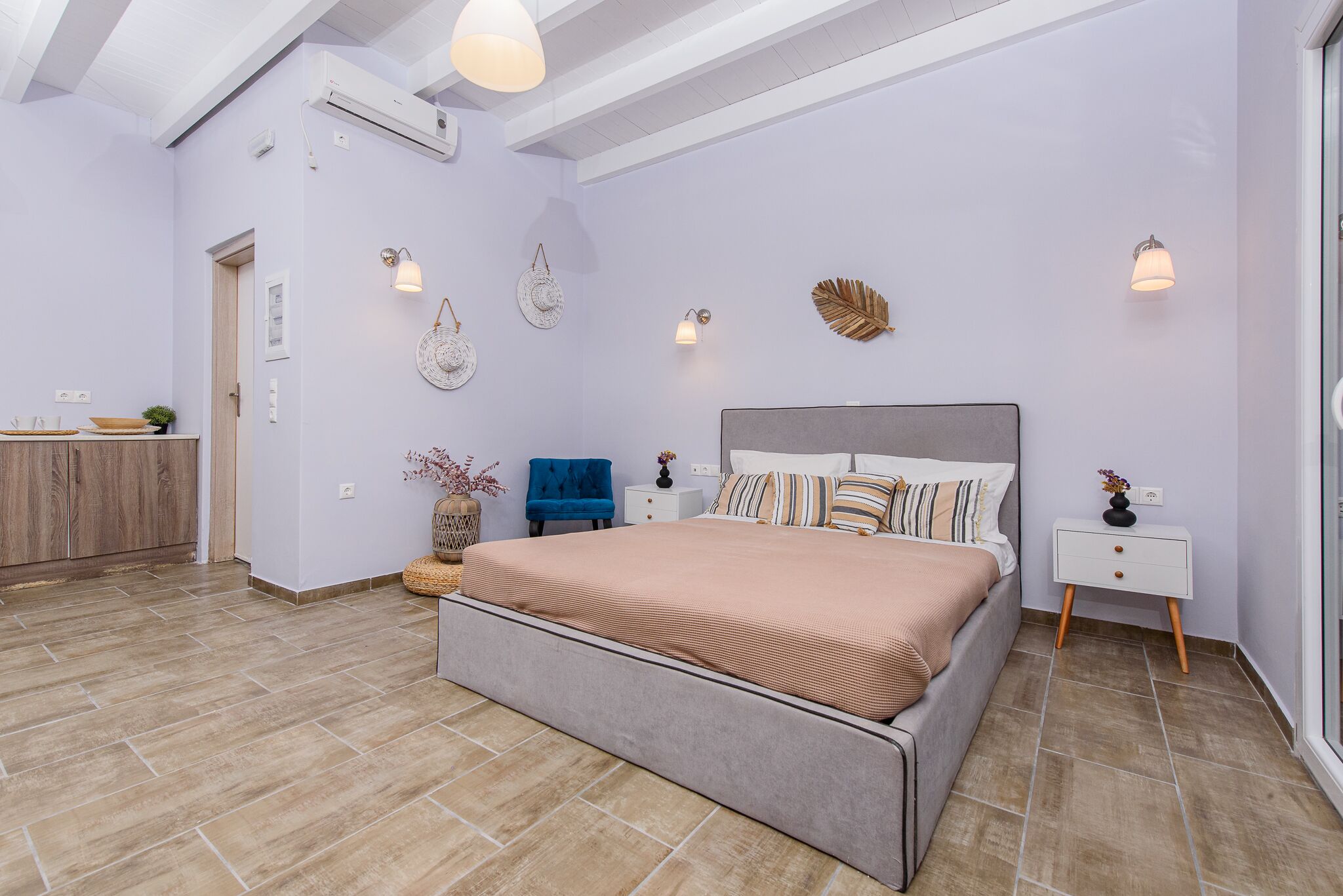 A bedroom with a large bed, bedside tables, wall decor, and a wooden wardrobe.