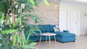 A modern living room with a blue sofa, a round coffee table, and a brick wall. - Villa Casa Kalandra ZadarVillas (Rovinj)
