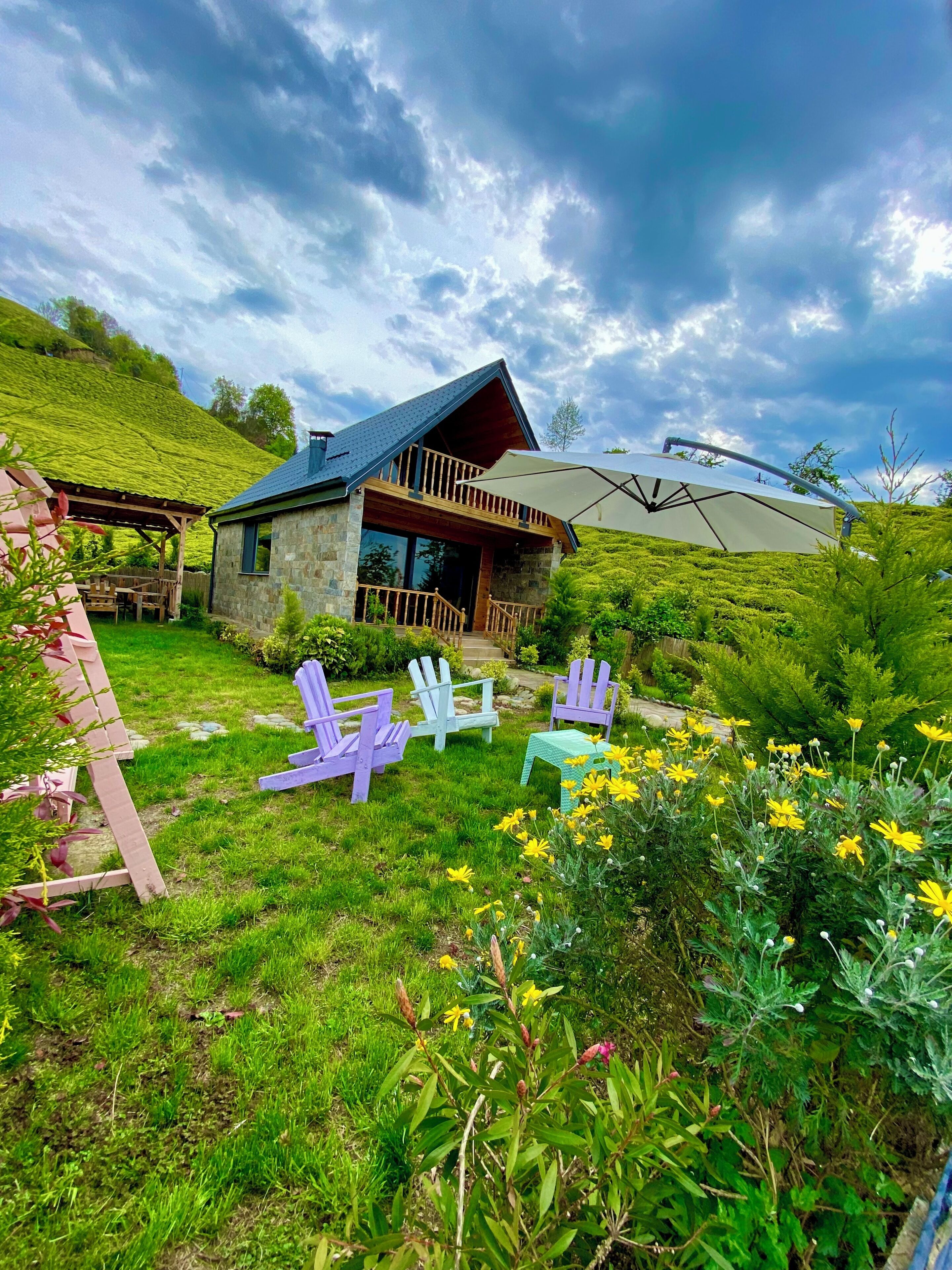 Una casa de piedra con un balcón y un jardín con sillas y flores.