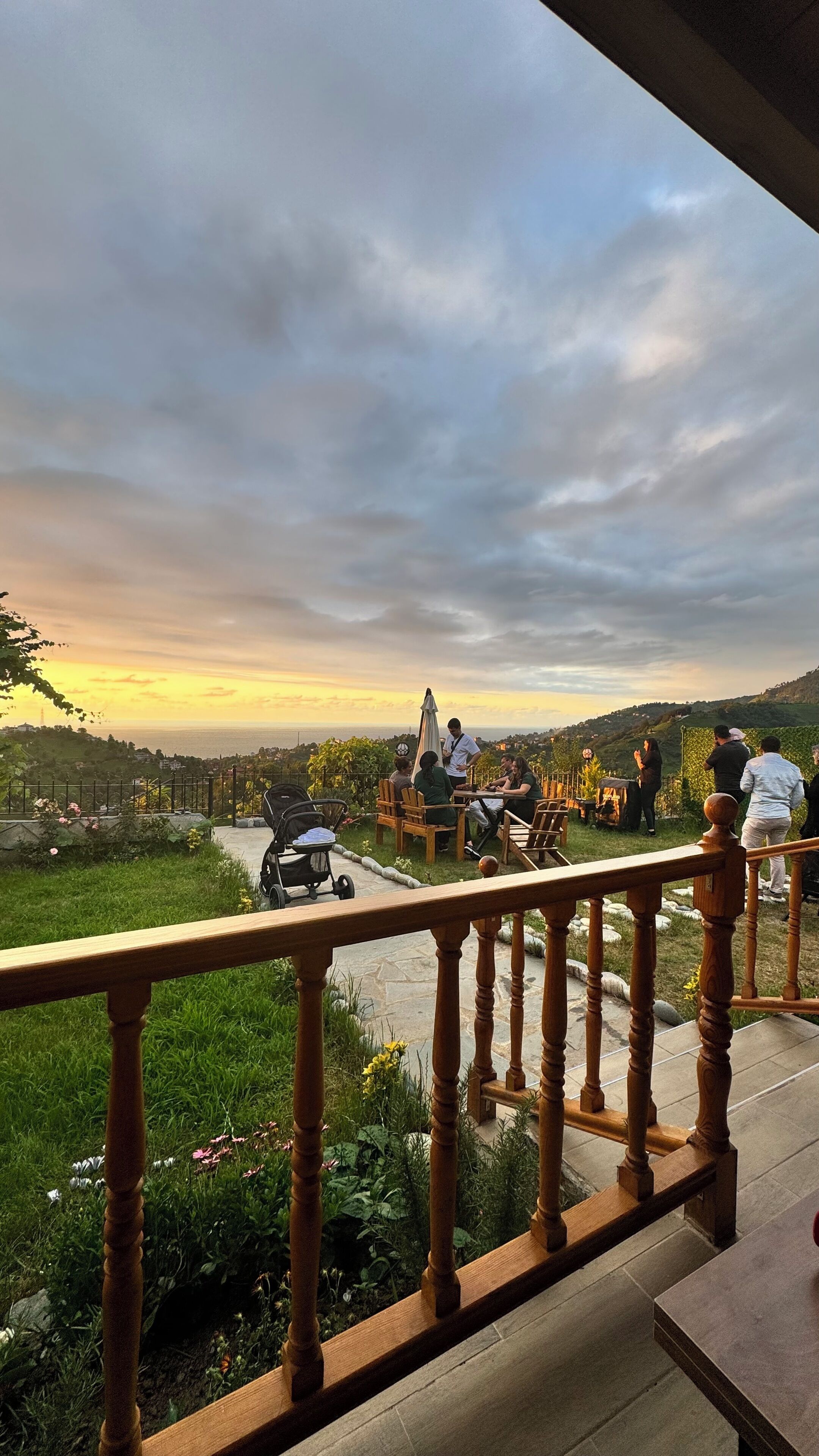 A balcony with a wooden railing overlooking a scenic landscape with a sunset view.