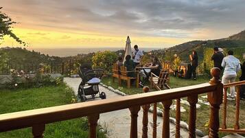 A balcony with a wooden railing overlooking a scenic landscape with a sunset view.