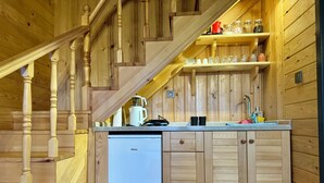 Een kleine keuken met houten kastjes, een witte koelkast en een inbouwfornuis.