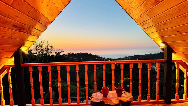 Een houten balkon met een tafel en stoelen, met uitzicht op een prachtig landschap.