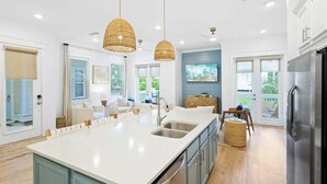 A modern kitchen with a large island, stainless steel appliances, and a dining area with a view.
