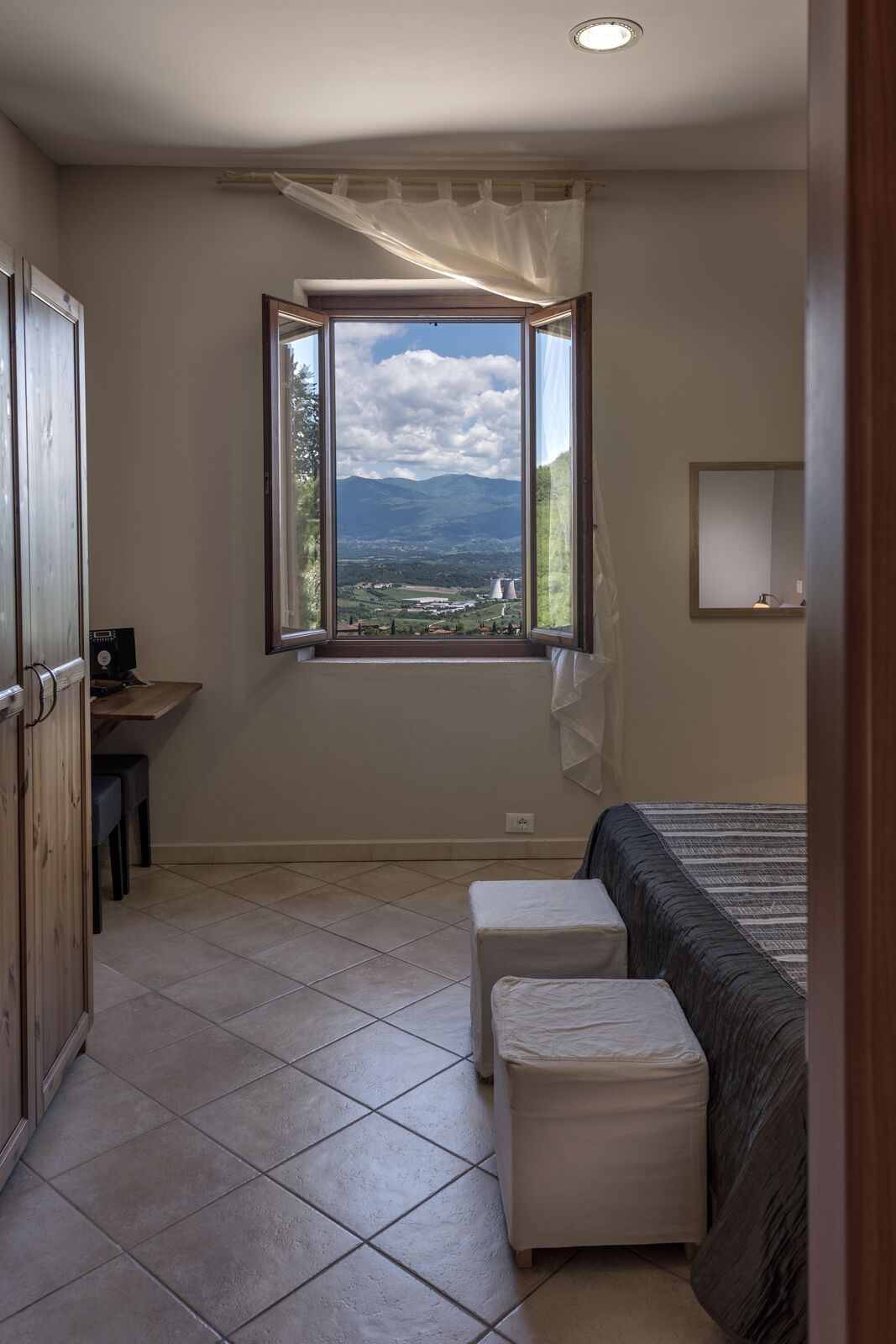 Ein Schlafzimmer mit großem Fenster, einem Bett, einem Nachttisch und einem Sessel.