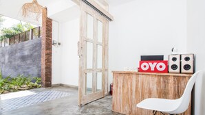 A room with a wooden desk, a white chair, and a red 'OYO' sign. - OYO 2896 Uma Menuh Guest House Near Pantai Keramas (Perean Tengah)