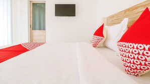 A hotel room with a bed, a TV, and a door. - OYO 2896 Uma Menuh Guest House Near Pantai Keramas (Perean Tengah)