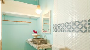 A bathroom with a toilet, a sink with a decorative basin, a hanging light fixture, and a tiled wall with a geometric pattern. - OYO 2896 Uma Menuh Guest House Near Pantai Keramas (Perean Tengah)