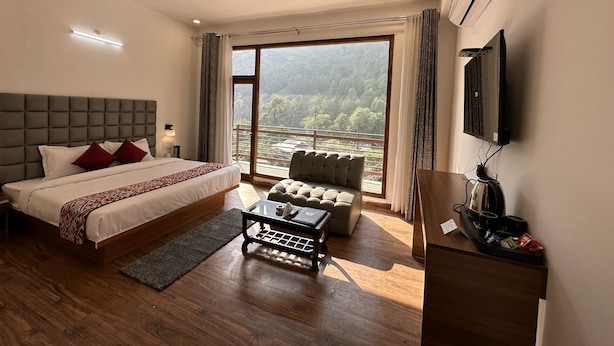 Une chambre d’hôtel moderne avec un grand lit, un canapé, une table basse et un téléviseur.