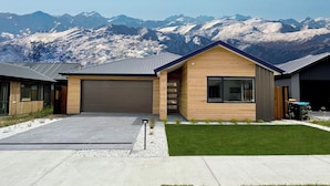 Ein modernes, zweistöckiges Haus mit Garage, gepflegtem Rasen und Bergblick.