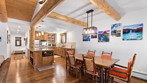 A spacious kitchen with wooden cabinets, a dining area with a wooden table and chairs, and a large island. - Ridge Court # 14 at Palisades - Ski Shuttle, Dog OK (Olympic Valley)