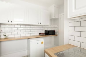 A kitchen with white cabinets, a microwave, a small refrigerator, and a wooden countertop. - Beautiful Central 4 Bedroom Apart next2 KingsCross (Greater London)