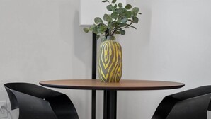 A round table with a vase of green plants and two black chairs. - Cozy 1BR Near Zoo, UC, Hospitals (Cincinnati)