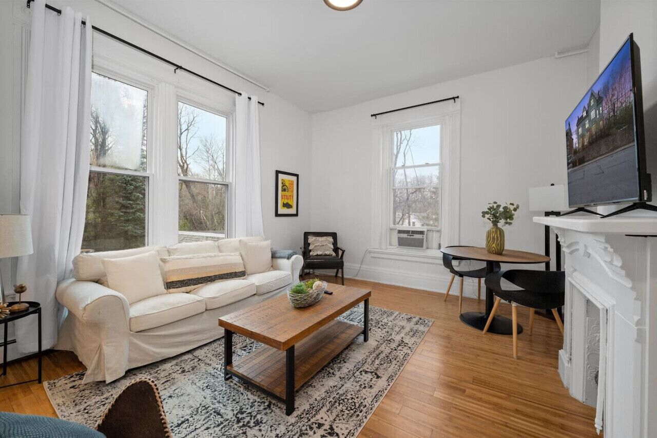 Un salon spacieux avec un canapé blanc, une table basse en bois et une cheminée.