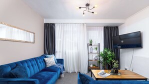 A modern living room with a blue sofa, a wooden coffee table, and a flat-screen TV. - Modern 4 Bed Apartment  next to Borough Station (Greater London)