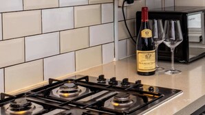 A kitchen with a gas stove, a wine bottle, and two glasses on the counter. - Modern 4 Bed Apartment  next to Borough Station (Greater London)