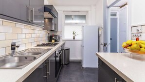 A modern kitchen with stainless steel appliances, a double sink, and a window with a plant. - Modern 4 Bed Apartment  next to Borough Station (Greater London)