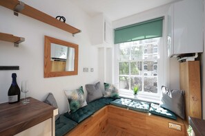 A modern kitchen with a built-in bench, a wine bottle, and a glass on the counter. - Modern 1 Bedroom Apartment  Next 2 Old Street St (London)