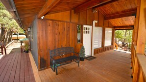 A wooden deck with a bench, a door, and a small Christmas tree. - Bear Paw- Lake Area  located in Willow Cove (Bass Lake)