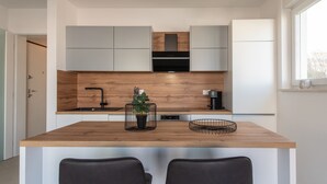 Eine moderne Küche mit einer Holz-Kochinsel, zwei schwarzen Stühlen und einem Blumentopf.