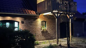 Una casa de dos pisos con fachada de piedra, un balcón y un camino de entrada adoquinado.