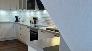 Una cocina moderna con armarios blancos, piso de madera y horno empotrado.