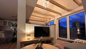 Una sala de estar moderna con televisor, una mesa de comedor y una planta.