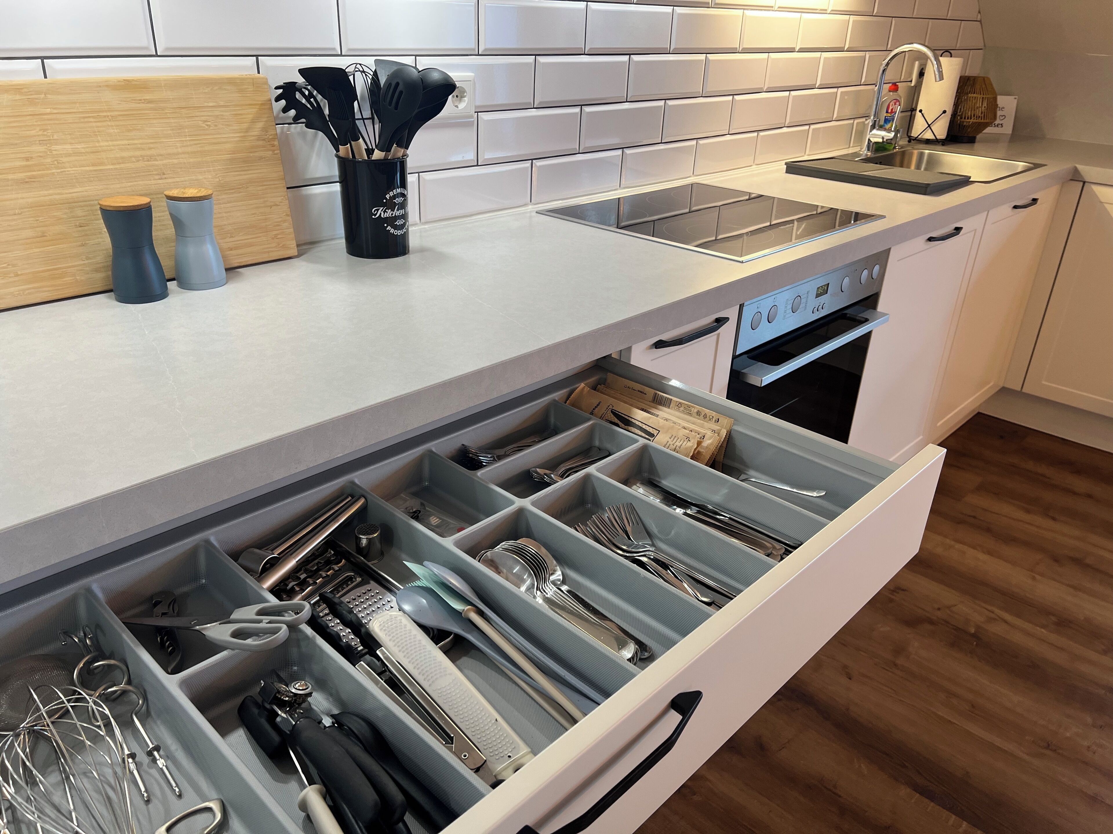 Een keuken met een ingebouwde vaatwasser, een spoelbak en een houten snijplank.