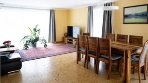 A dining area with a wooden table and chairs, a TV, and a potted plant. - Ferienhaus Marina (Weil am Rhein)