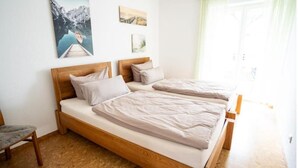 A double bed with wooden headboard, a small chair, and a painting of a mountain landscape on the wall. - Ferienhaus Marina (Weil am Rhein)
