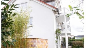 A modern two-story building with a stone base and a white upper section. - Ferienhaus Marina (Weil am Rhein)