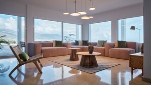 Una sala de estar moderna con ventanas amplias, un sofá, una mesa de centro y un sillón.