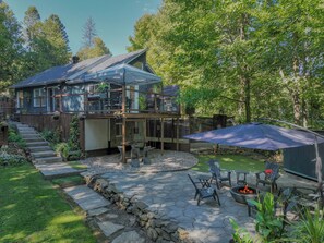 A two-story house with a covered patio area, stone steps leading to the entrance, and a fire pit with seating. - Available exclusively for Winter 2027, from January 15 to March 13. Short or long stays for a peaceful getaway in the heart of the Laurentians. (Prévost)
