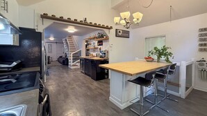 A modern kitchen with a central island, bar area, and a staircase leading to an upper level. - Availability limited to Winter 2027 (from January 15th to March 13th, 2027) short or long term 2 months, for a serene escape in the heart of the Laurentians. (Prévost)