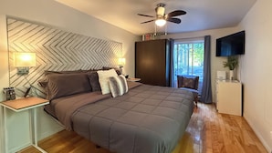 A modern bedroom with a large bed, a ceiling fan, a TV, and a view of the outdoors. - Availability limited to Winter 2027 (from January 15th to March 13th, 2027) short or long term 2 months, for a serene escape in the heart of the Laurentians. (Prévost)