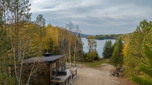 A modern cabin with a deck overlooking a lake, surrounded by autumn trees. - Magnificent chalet with a contemporary design: dream location for an unforgettable holiday (Notre-Dame-de-la-Merci)