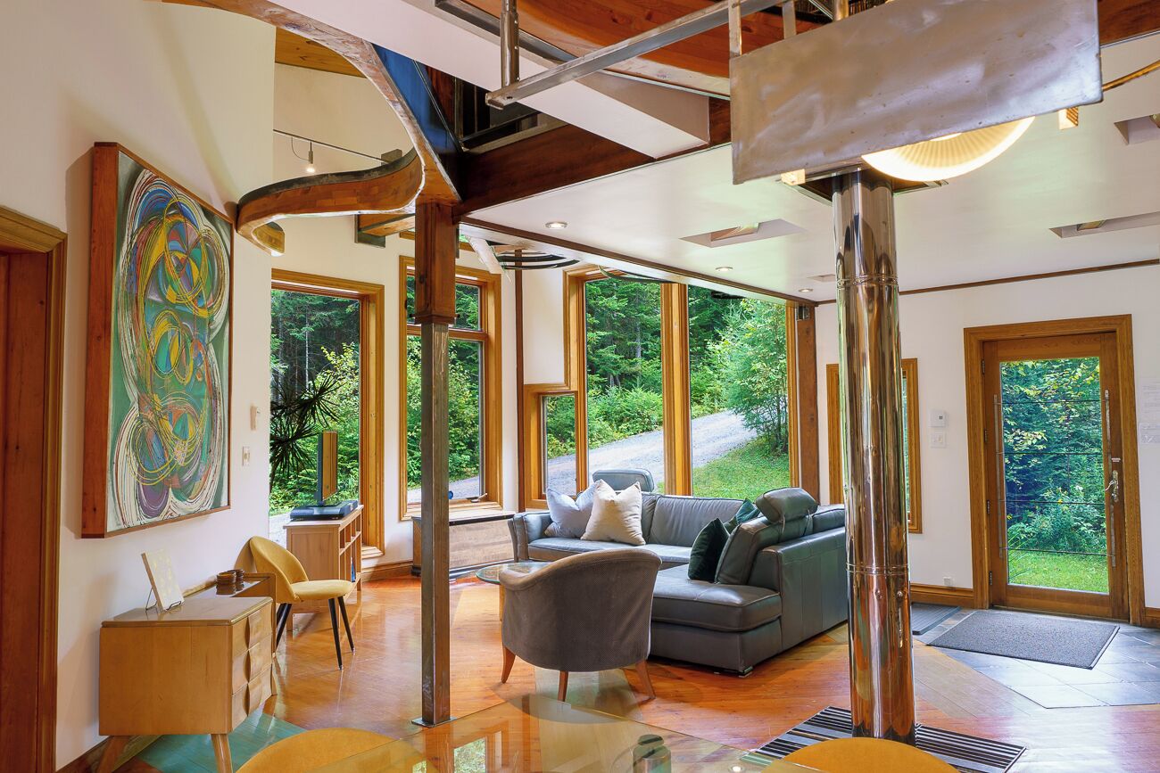 A spacious living area with a large window, a gray sofa, and a wooden desk.