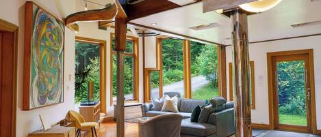 A spacious living area with a large window, a gray sofa, and a wooden desk.