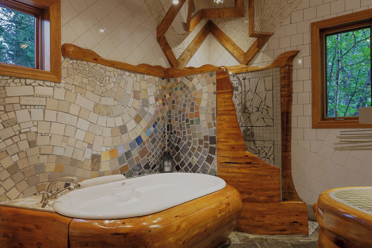 A bathroom with a wooden bathtub, mosaic tile walls, and a wooden ceiling structure.