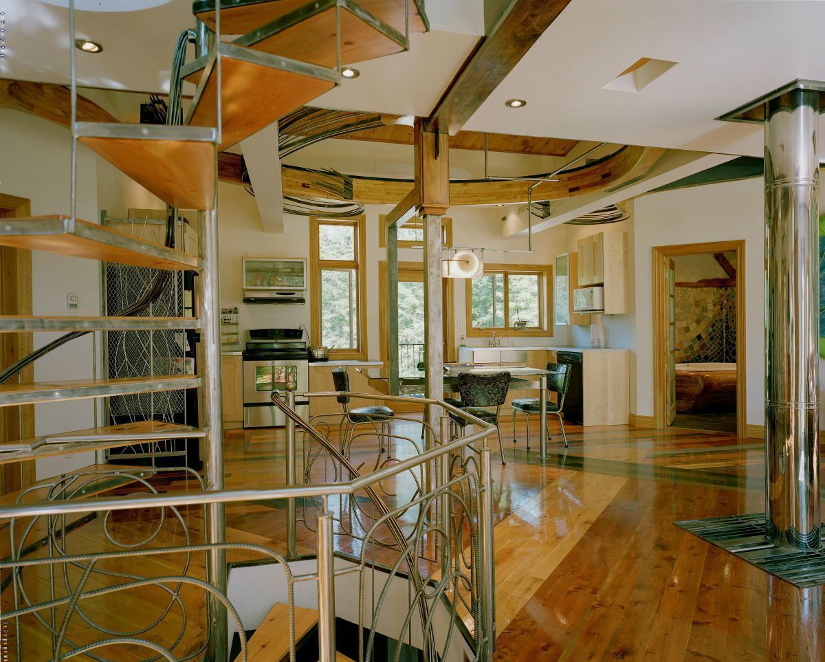 A spacious interior with a wooden staircase, a dining area, and large windows allowing natural light.