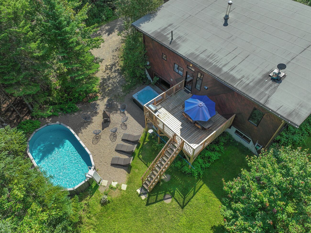 An aerial view of a house with a swimming pool, a deck with outdoor seating, and a satellite dish.
