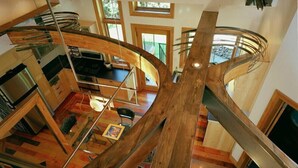 A modern interior with a central spiral staircase, wooden flooring, and a kitchen area.