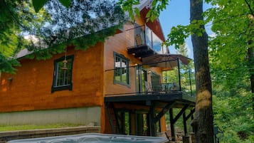 Une cabane en bois dotée d’un bain à remous, d’un balcon et d’une terrasse.