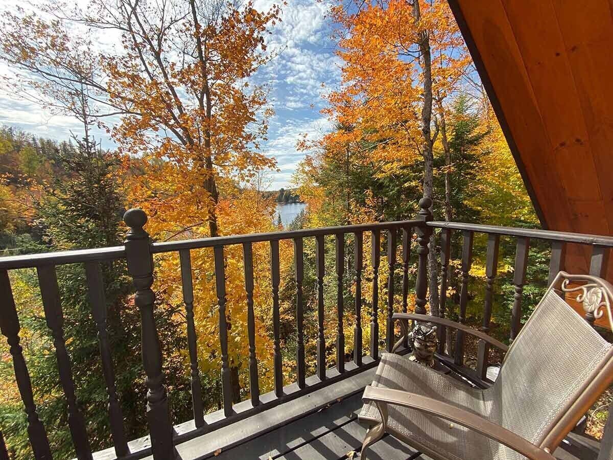 A balcony with a chair, surrounded by autumn foliage.